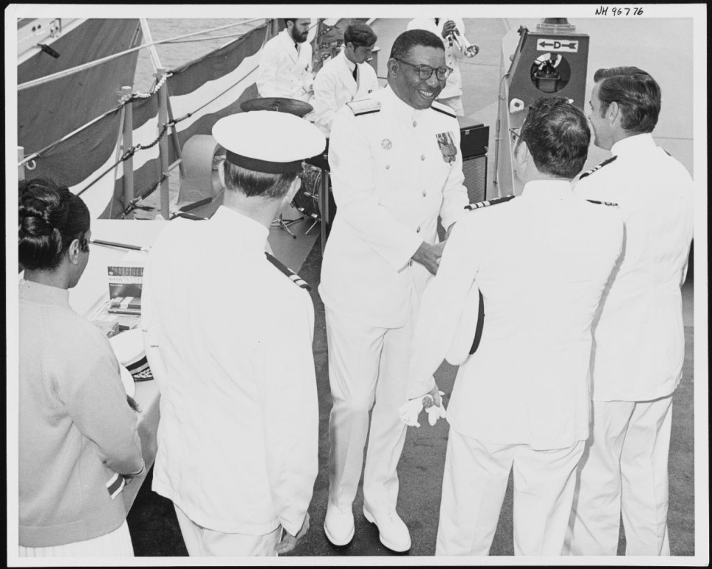  (Center) Receives the congratulations of other officers, following the ceremony marking his promotion to flag rank, on board USS Jouett (DLG-29) at San Diego, California, 2 June 1971. Prior to his promotion to Rear Admiral, Captain Gravely was Jouett's Commanding Officer. U.S. Naval History and Heritage Command Photograph. 